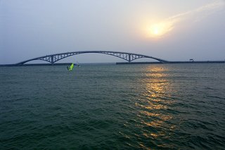 夕陽西下，橋下的風帆顯得孤寂