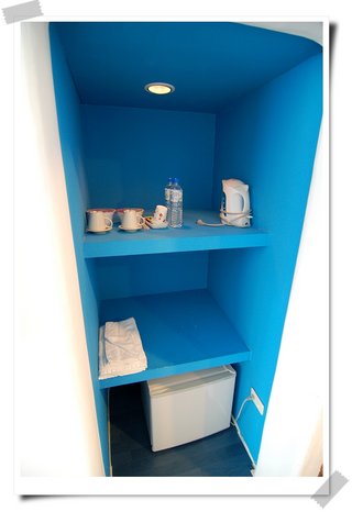 造型小櫃子上擺有茶杯、茶壺、毛巾、冰箱等基本用具(蜜月套房)