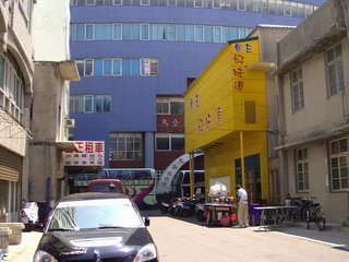 港務局碗粿的攤位就擺在港務局大樓旁這棟黃色屋子下，不要看到黃色屋子就說：哇！燦坤嘛
